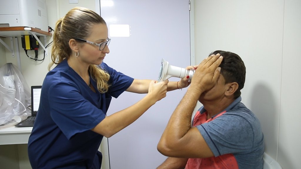 Médica examinando um paciente utilizando o Retinógrafo Portátil Eyer da Phelcom Technologies.
